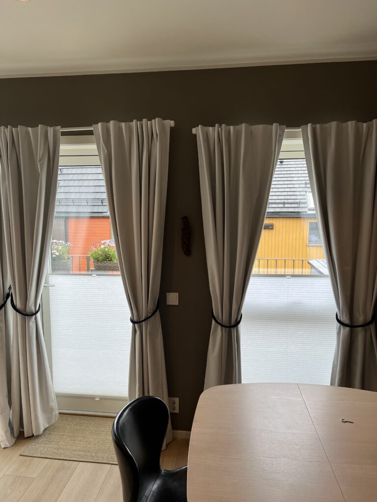 Gardiner og liftgardin som gir myk lysdemping ved spiseplass med stort vindu.