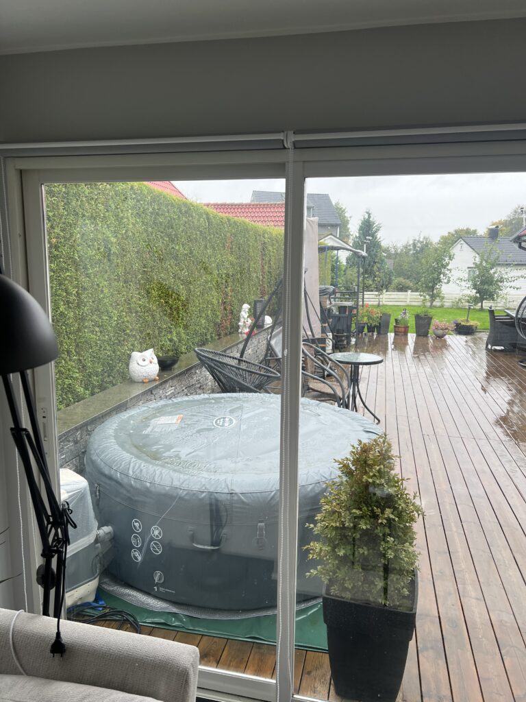 Lys innvendig screen foran vindu med utsikt mot en hage