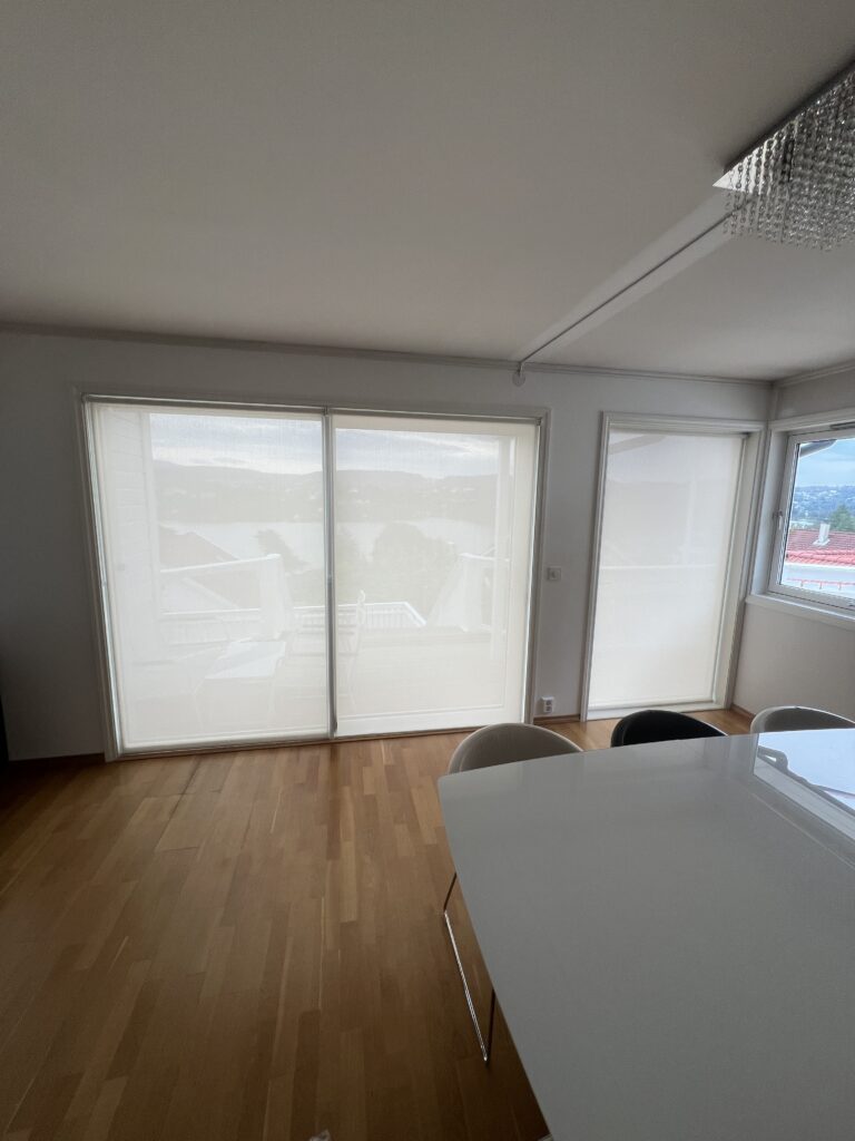Innvendige screen som demper sollys på store vindusflater i moderne rom.