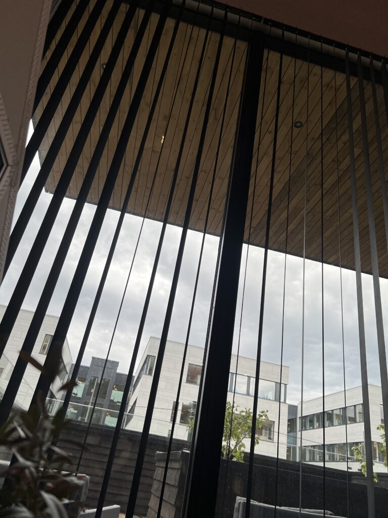 Lamellgardiner foran store vinduer som gir regulerbar lyskontroll og innsynsskjerming.