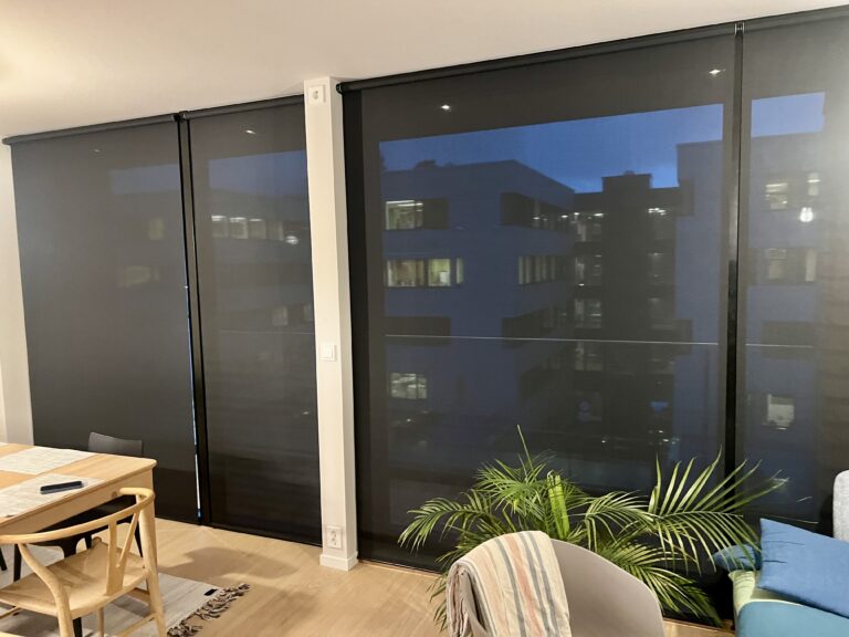 Innvendige screen som demper lys og innsyn foran store vinduer i moderne stue.