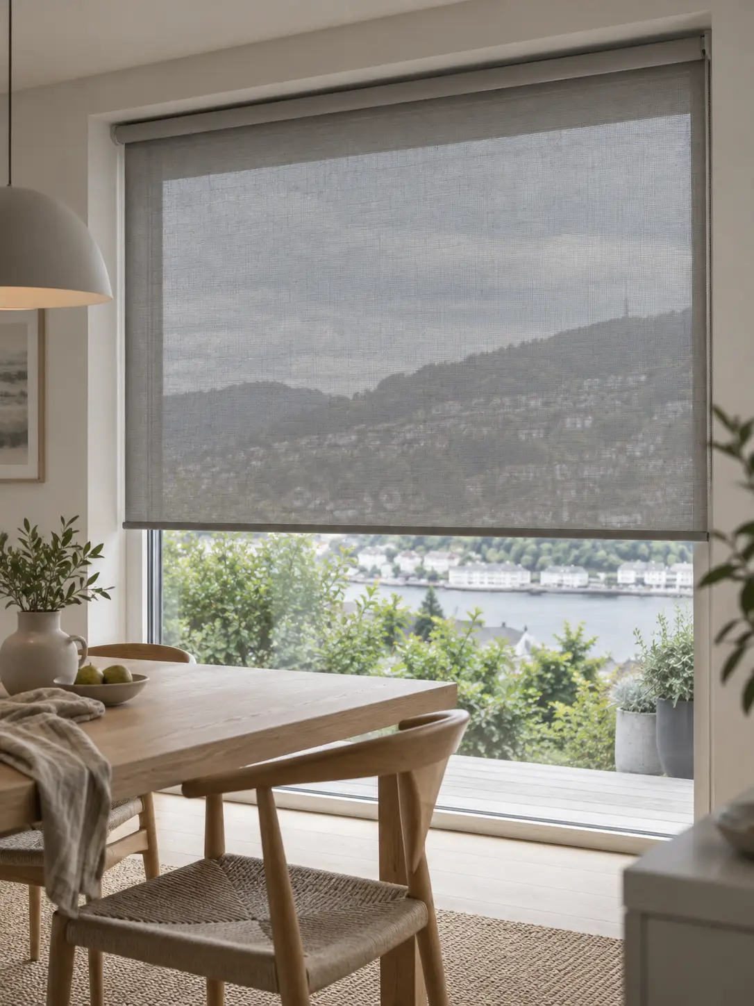 Innvendig screen i grå tekstil montert foran et stort vindu i en moderne spisestue i Bergen